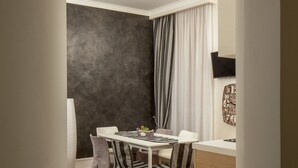 A modern dining area with a white table, striped chairs, and a grey sofa. - I Fiumi Di Navona (Rome)