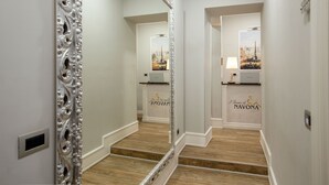 A hallway with a large ornate mirror, a staircase, and a wall with a logo. - I Fiumi Di Navona (Rome)