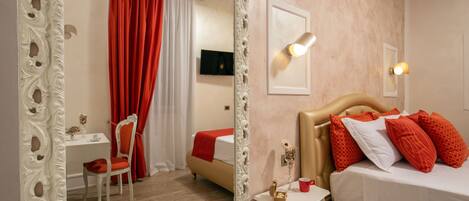 A hotel room with a bed, a desk, a chair, and a mirror.