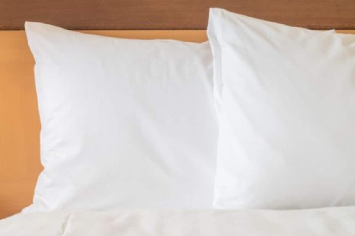 A bed with white bedding and a wooden headboard.