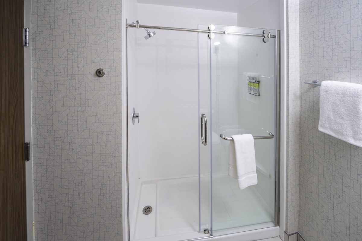 A glass-enclosed shower with a towel rack and a visible shower control panel.