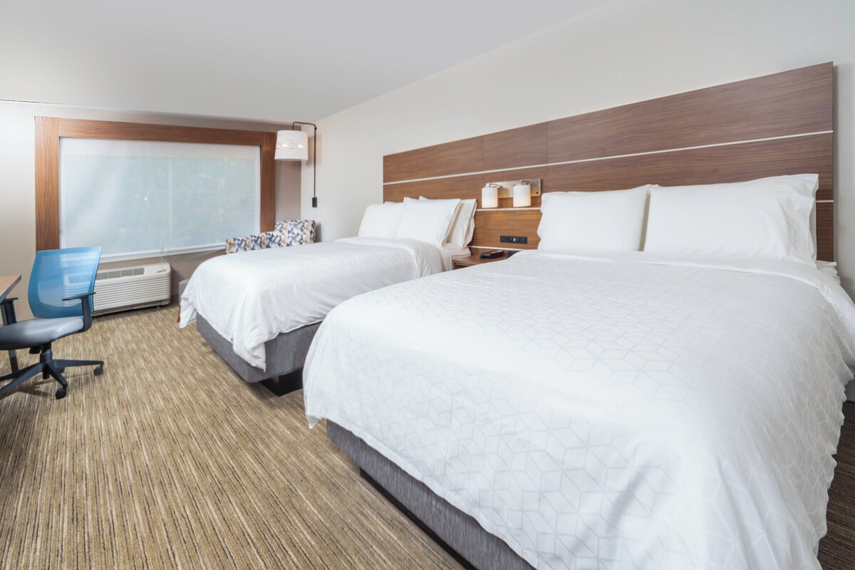 A hotel room with two beds, a desk, and a chair.