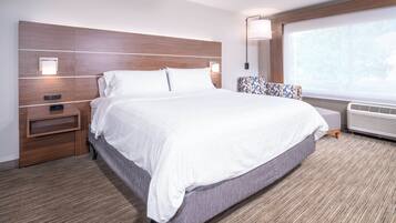 Une chambre d’hôtel avec un grand lit, une table de chevet, une lampe, une fenêtre donnant sur un beau paysage et un radiateur intégré.