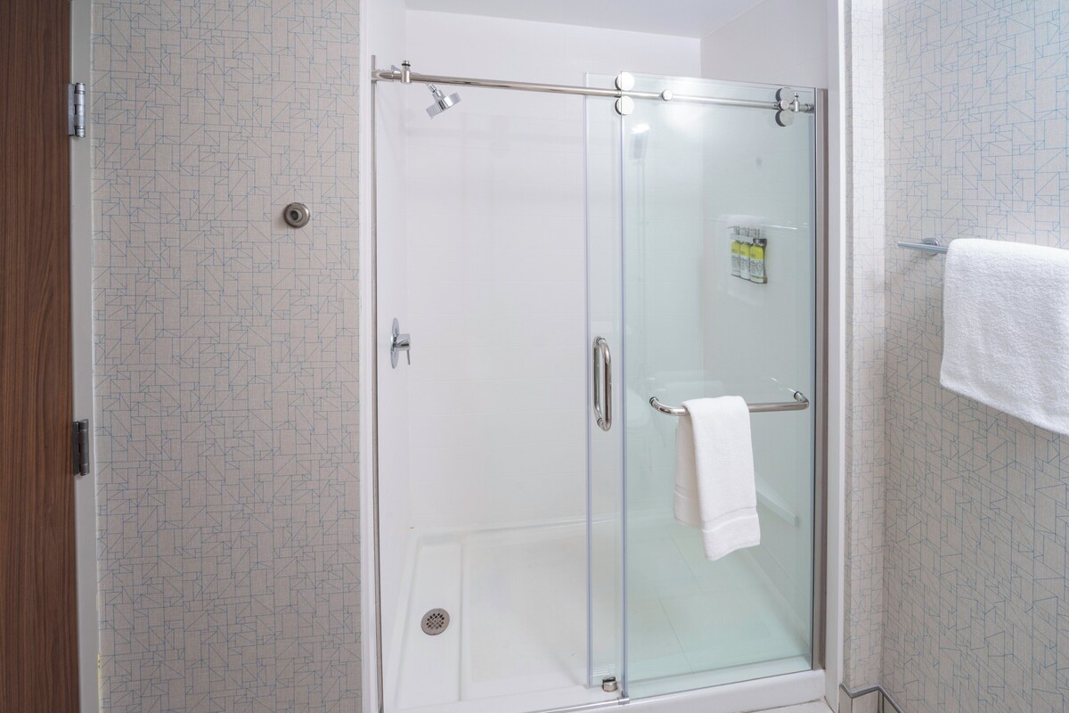 A glass-enclosed shower with a towel rack and a visible shower control panel.