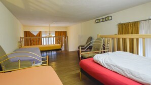 Een kamer met twee bedden, een stoel en een raam met gordijnen.