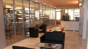Een moderne bibliotheek met glazen wanden, zwart meubilair en een betegelde vloer.