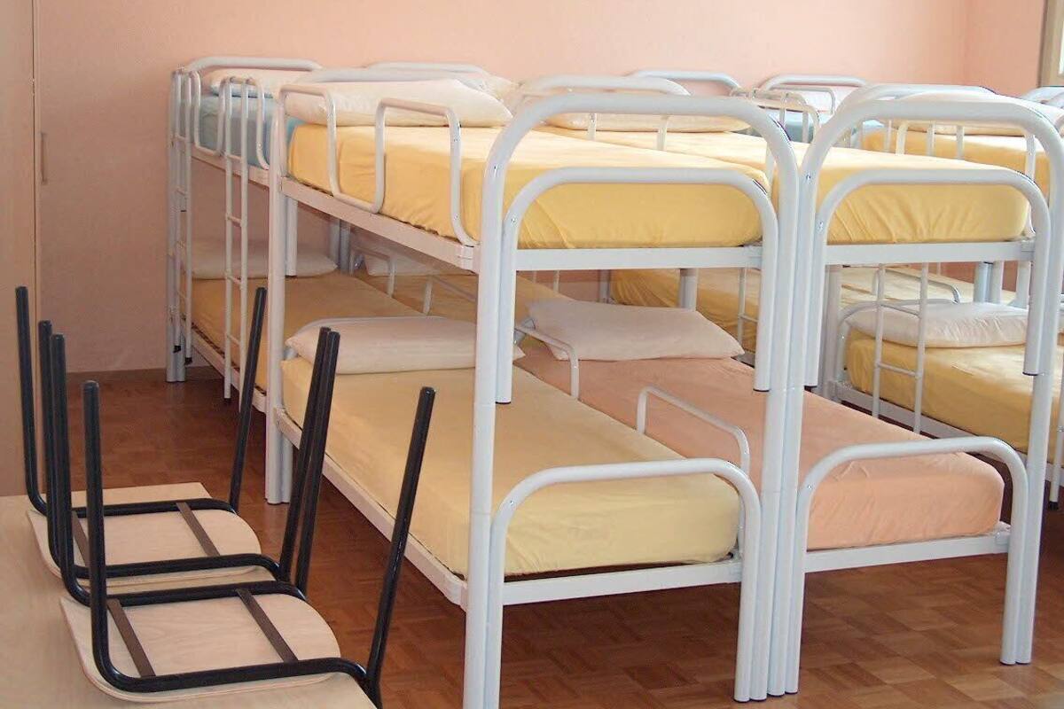 Une pièce avec des lits superposés disposés en deux rangées, chaque lit étant équipé d’un matelas et d’un oreiller.