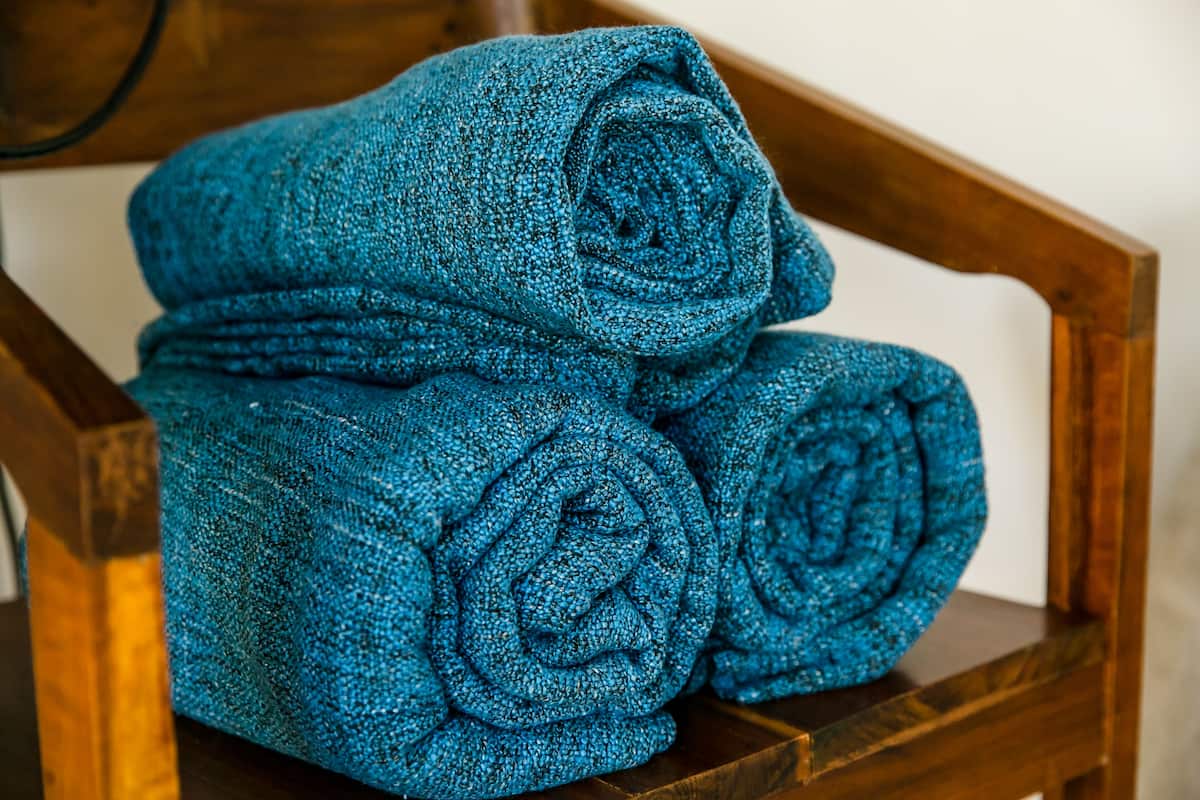 A stack of rolled blue towels on a wooden chair.