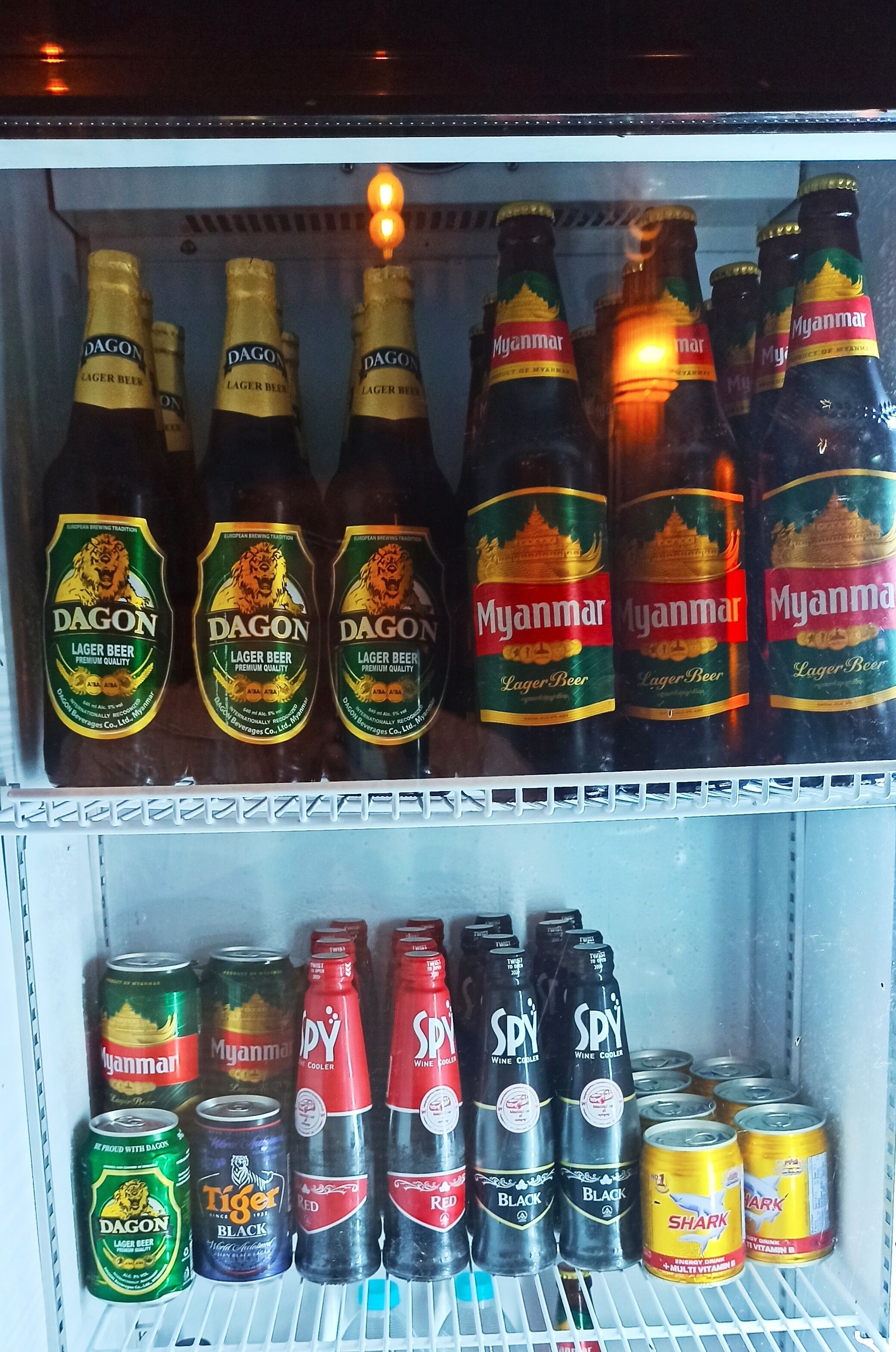 Jääkaappi on täynnä erilaisia juomia, mukaan lukien useita pulloja ja tölkkejä Myanmarin lagerolutta.