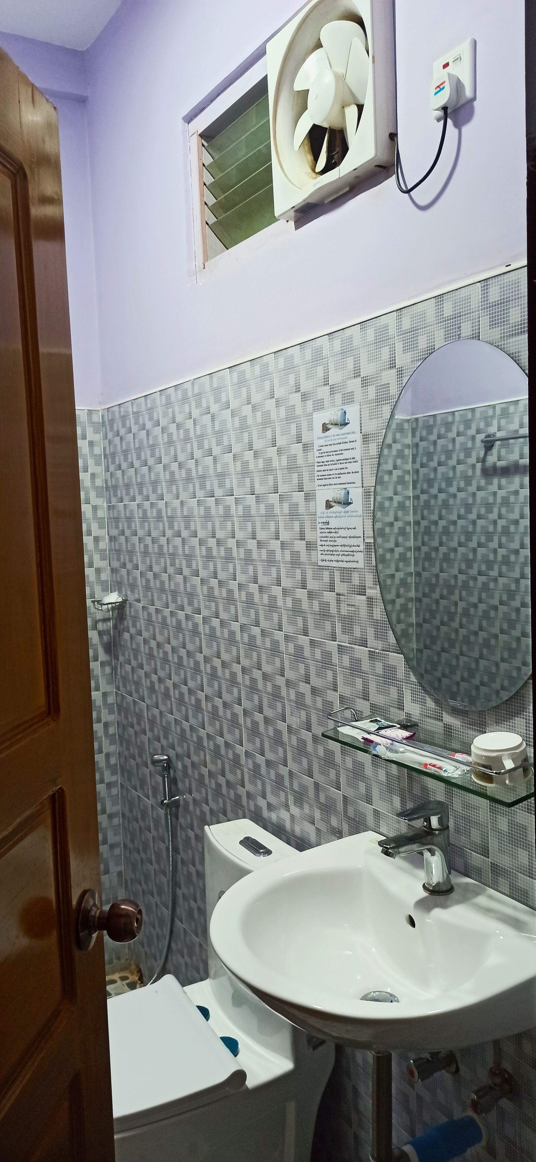 Uma casa de banho com lavatório branco, espelho, chuveiro e sanita.