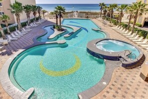 A pool area with a crescent moon design, lounge chairs, palm trees, and a view of the ocean. - Crystal Tower 1109 2 Bedroom Condo by RedAwning (Gulf Shores)