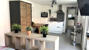 A compact living space with a bed, a wooden dining table, and a kitchenette in the background. - Vacation home with 3 bedrooms, furnished. Garden, 2 bathrooms, 2 kitchens, 200 meters from the beach (Egmond aan Zee)