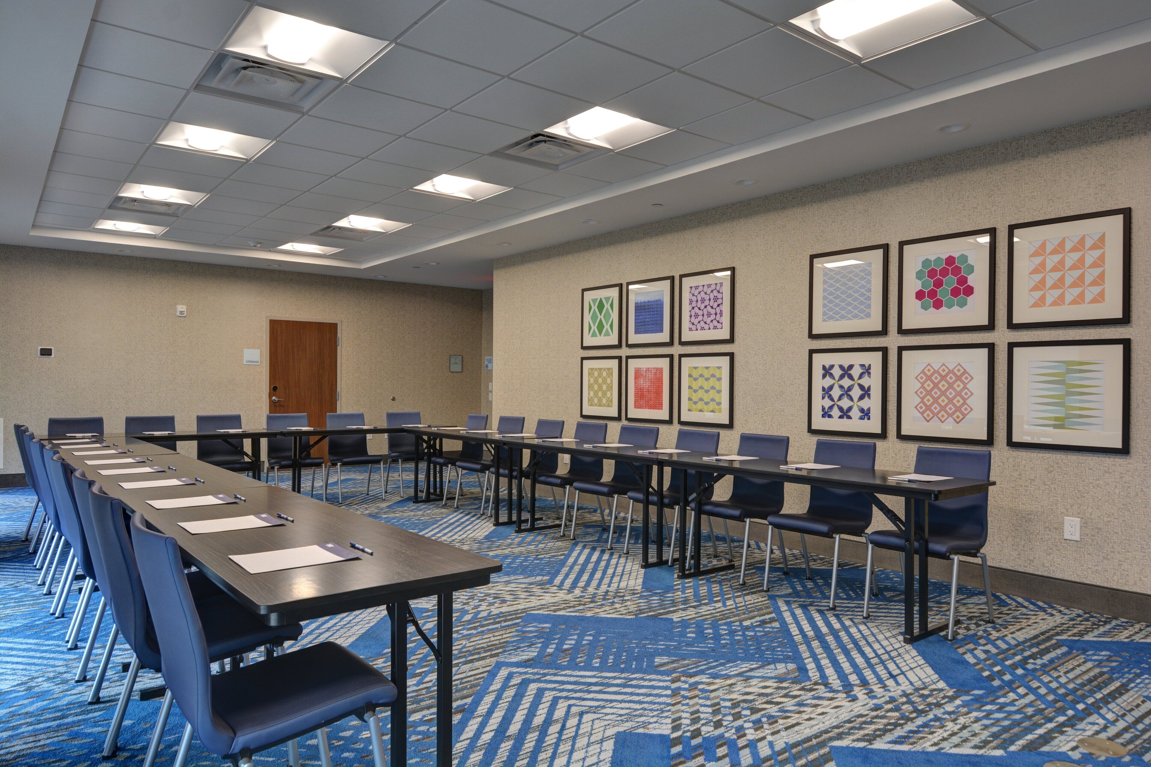 A conference room with a long table, chairs, and framed artwork on the walls.