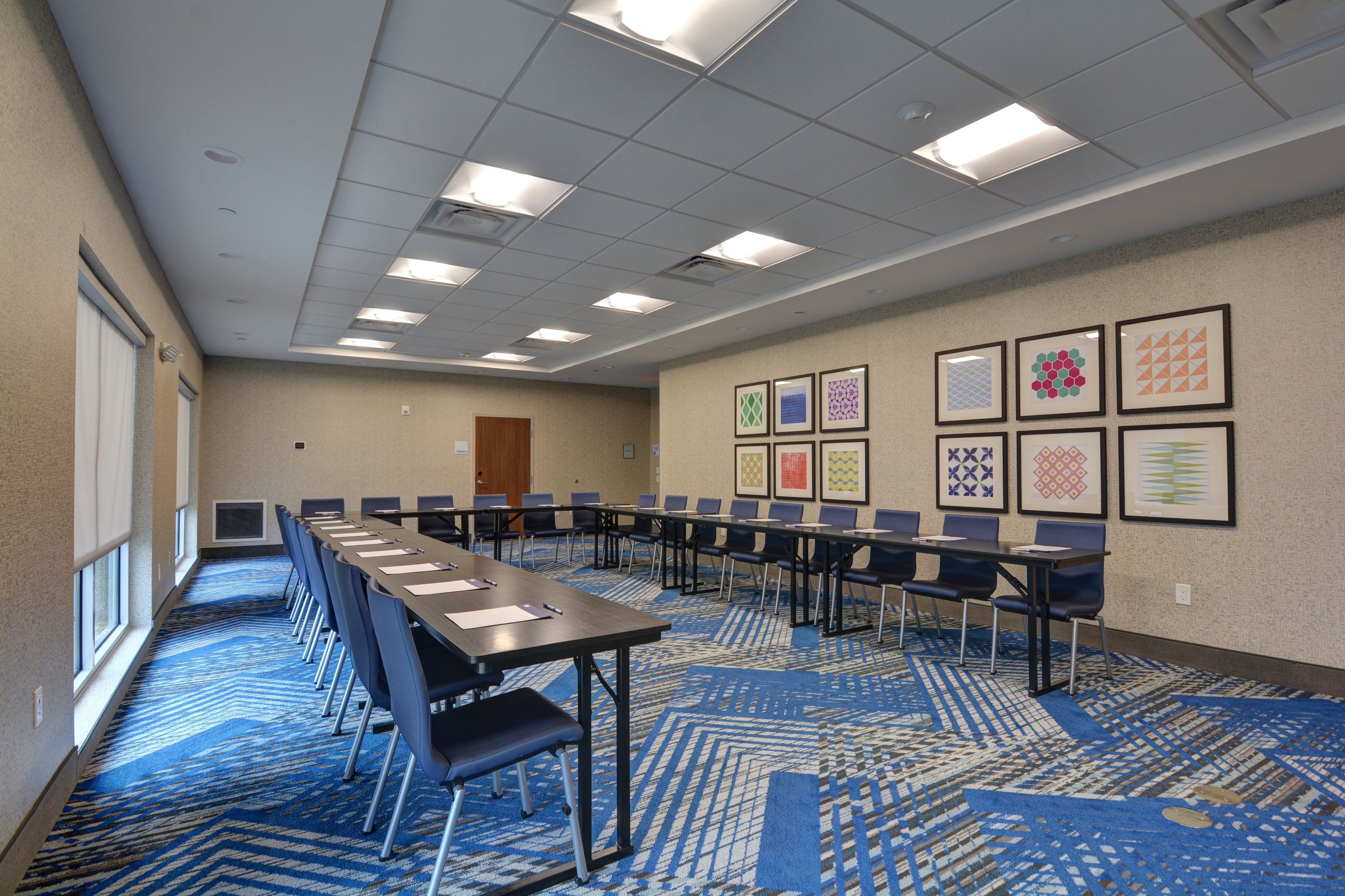 A conference room with a long table, chairs, and a patterned carpet.