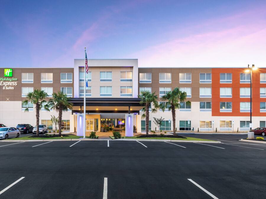 A Holiday Inn Express & Suites hotel with a parking lot and a clear sky.