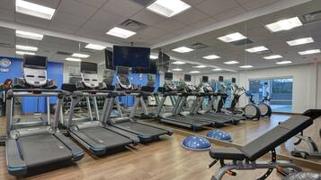 A gym with multiple treadmills, exercise balls, and a bench.