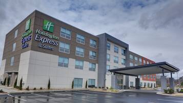 Un hotel Holiday Inn Express & Suites con un diseño moderno, que cuenta con un amplio estacionamiento y una entrada techada.