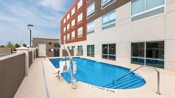 An outdoor swimming pool with a lifeguard stand, a diving board, and a no diving sign.