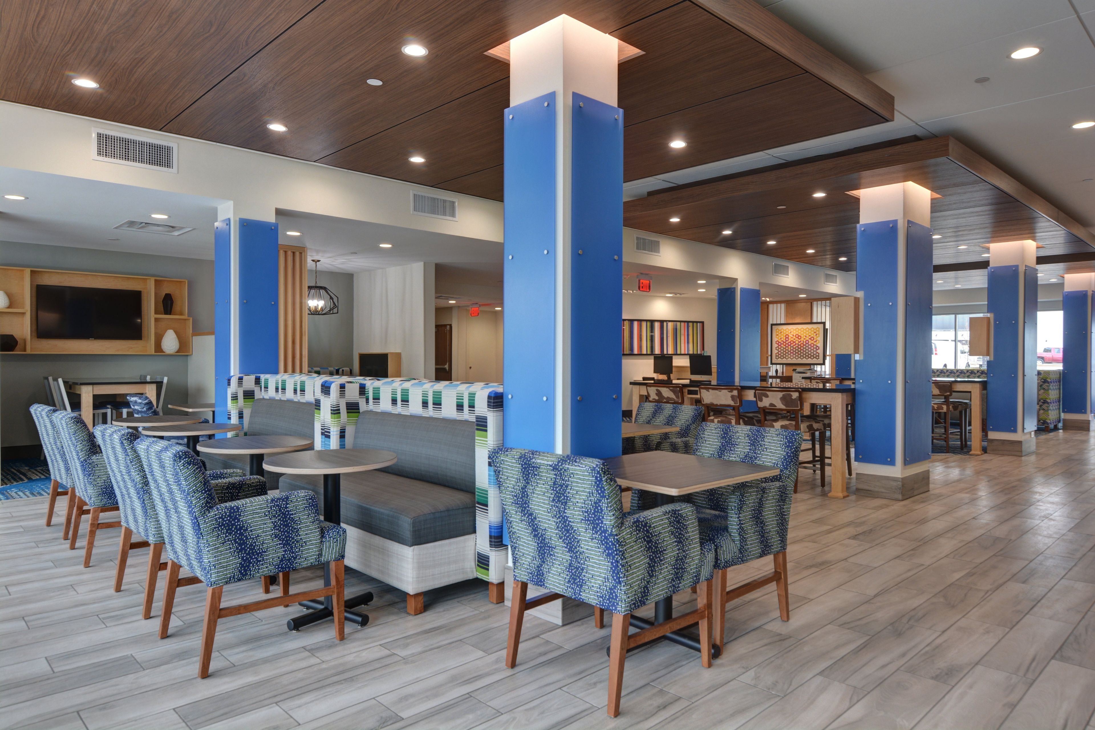 A modern restaurant with booths, tables, and high ceilings with recessed lighting.