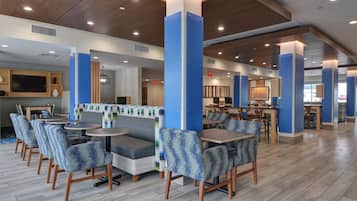 A modern restaurant with booths, tables, and high ceilings with recessed lighting.