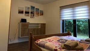 A bedroom with a bed, a desk, and a window with blinds.
