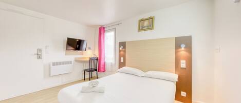 A modern hotel room with a large bed, a desk with a chair, a flat-screen TV mounted on the wall, and a window with pink curtains.