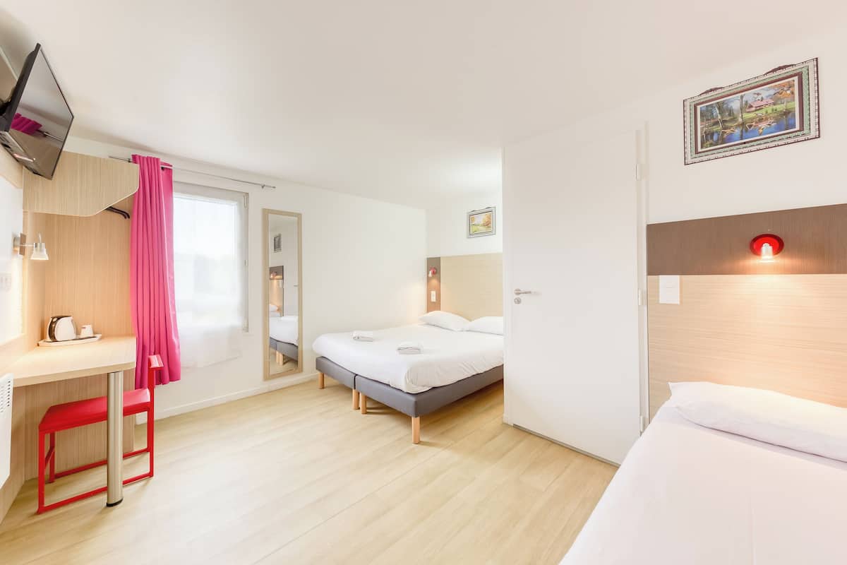 Een moderne hotelkamer met een bed, een bureau met stoel, een televisie en een schilderij aan de muur.