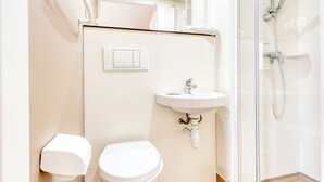 Une salle de bain avec des toilettes, un lavabo et une douche.