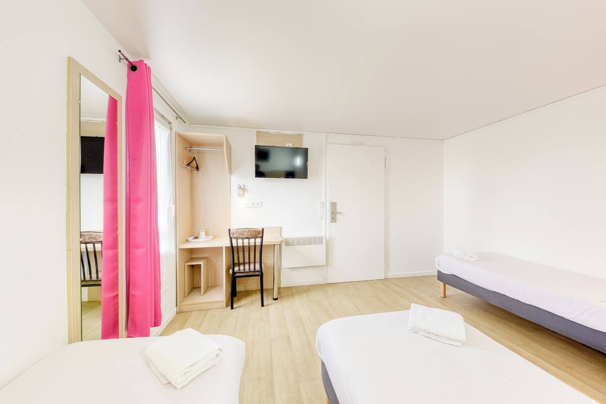 Een moderne hotelkamer met een bed, een bureau, een stoel, een televisie en een douche.