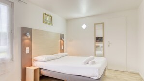 Une chambre à coucher moderne avec un lit, une table de chevet et un miroir.