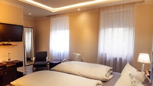 A hotel room with two beds, a TV, a desk, and a chair. - Hotel & Restaurant Peking (Riesa)