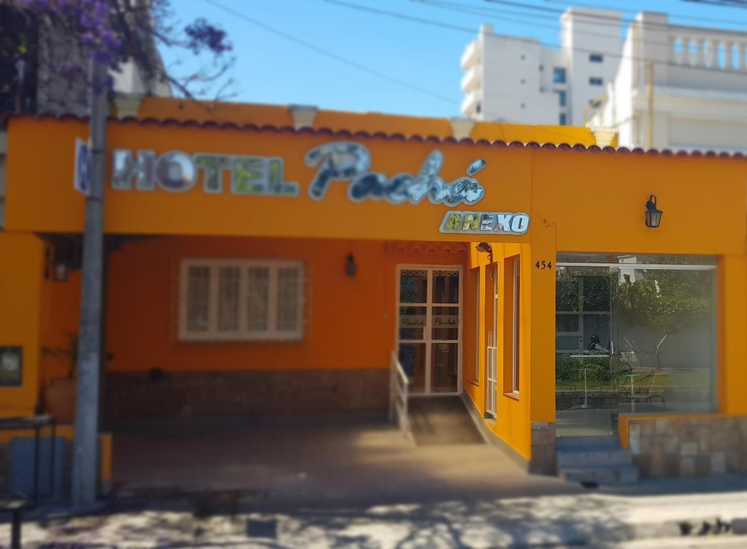 Un edificio amarillo con un letrero que dice "HOTEL Pacha" y "ANEXO" en la fachada.