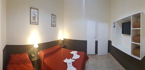 Una camera d'albergo con due letti, un armadio e un televisore.
