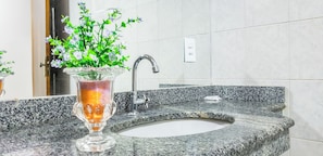 A bathroom with a granite countertop, a sink, a faucet, and a vase with flowers. - Bem Bahia Hotel (Santa Cruz Cabralia)
