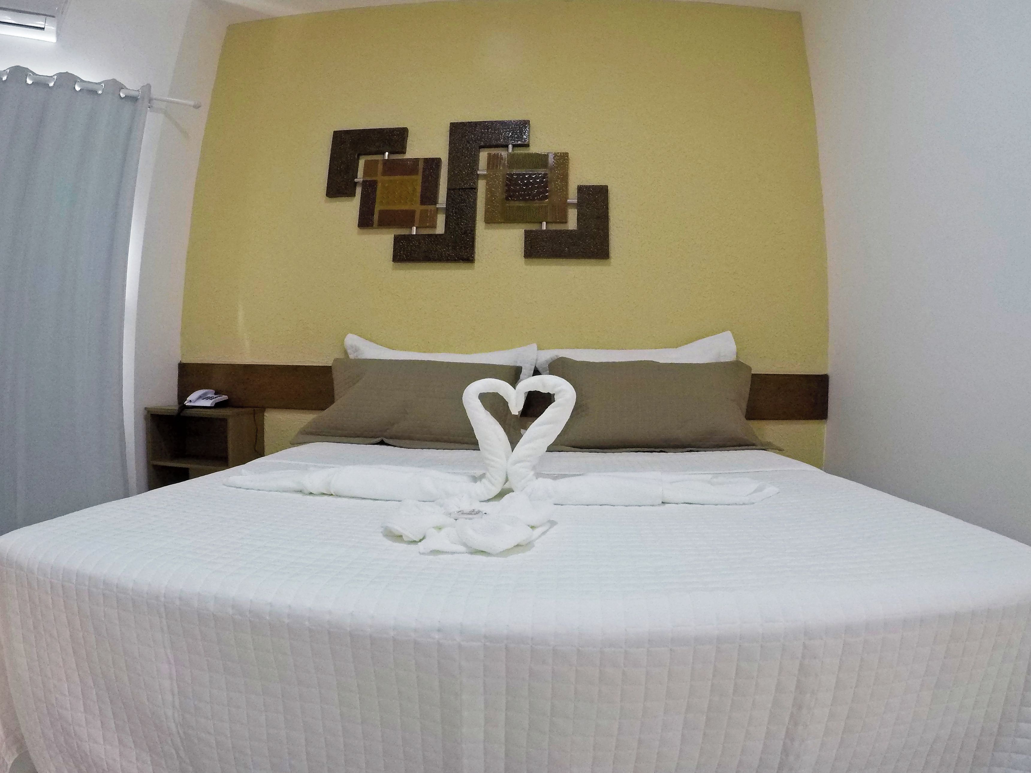 A hotel room with a bed, a wall-mounted artwork, and a telephone on a bedside table.