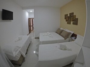 A hotel room with two beds, a TV mounted on the wall, and a door leading to another room. - Bem Bahia Hotel (Santa Cruz Cabralia)