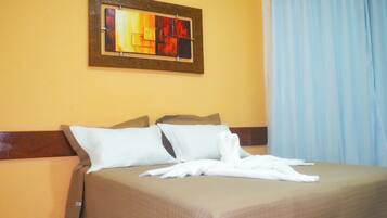 Una habitación de hotel con una cama, almohadas, una colcha y un cuadro en la pared.