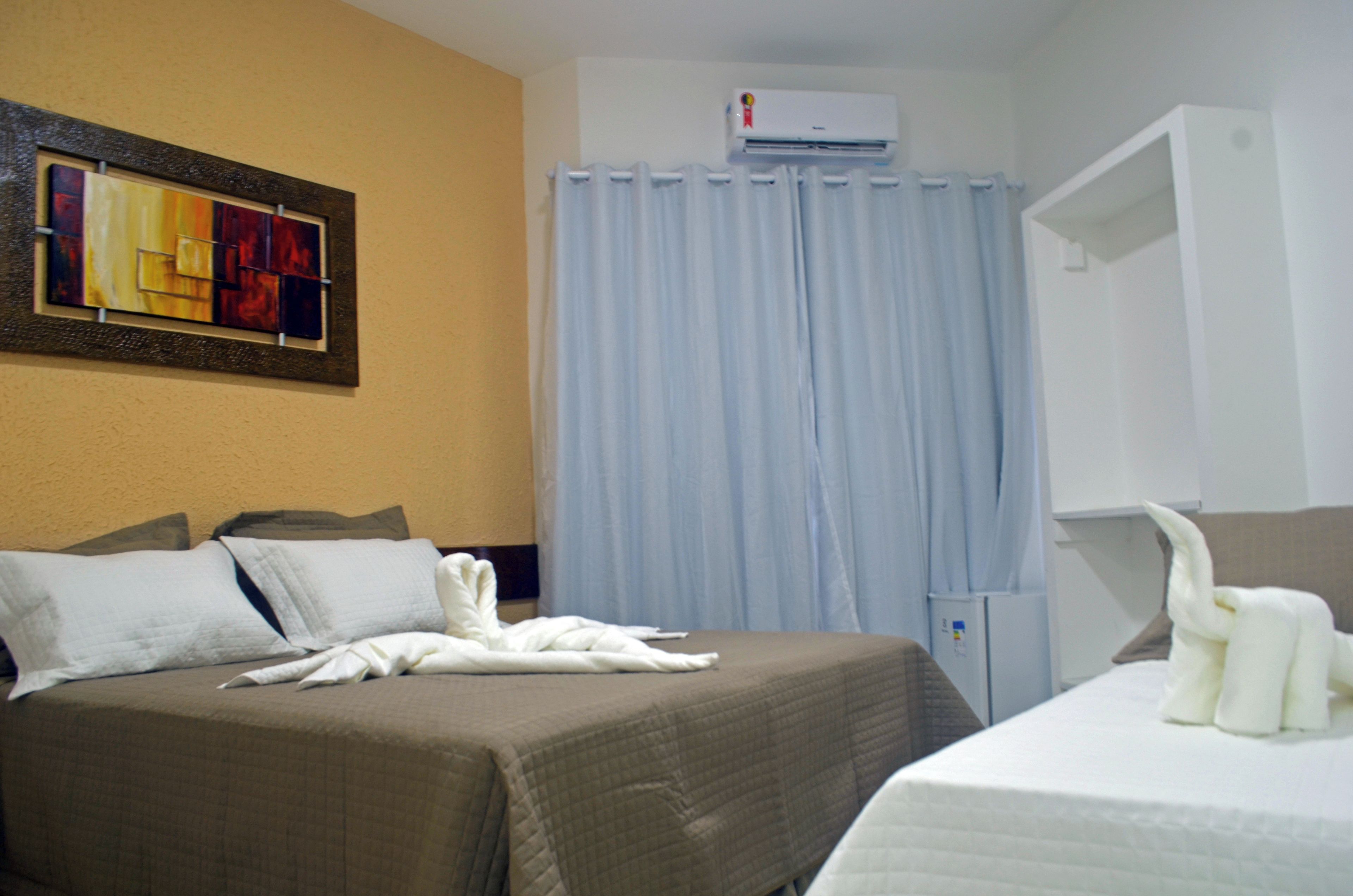 Ein Hotelzimmer mit Bett, Wandklimaanlage, Vorhang und Handtuchhalter.