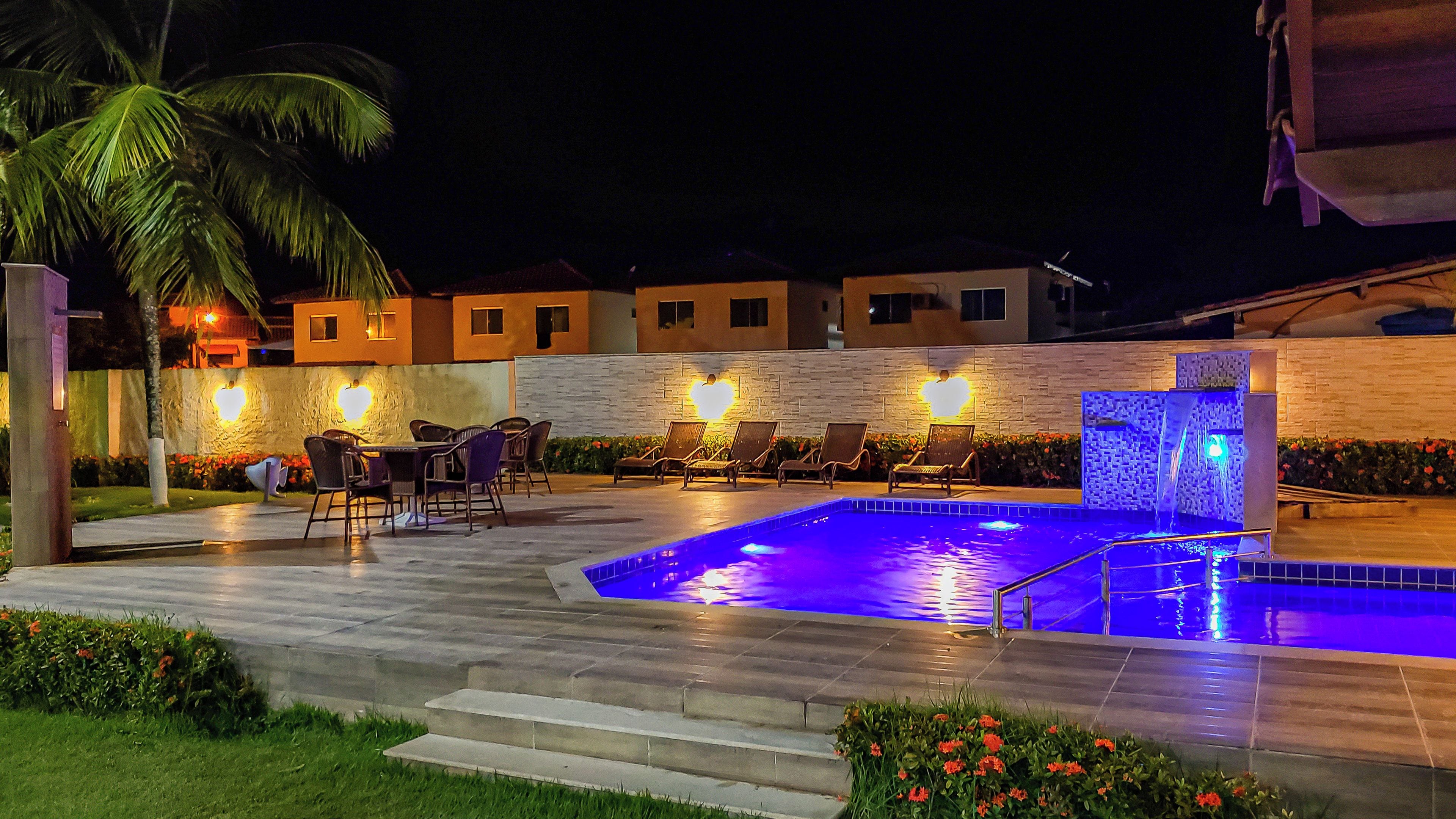 An outdoor swimming pool area with lounge chairs and a stone wall.