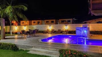An outdoor swimming pool area with lounge chairs and a stone wall.