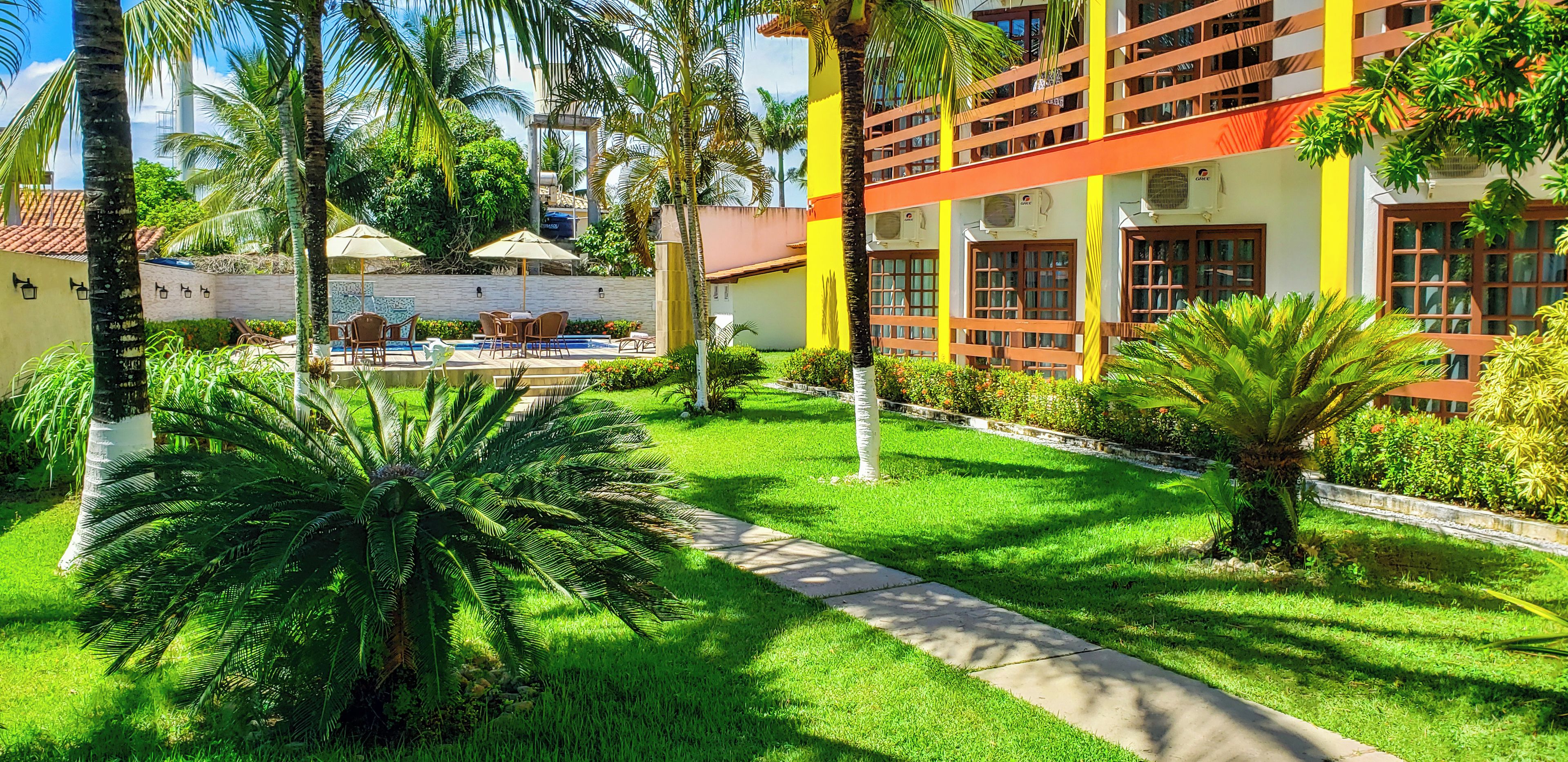 A hotel courtyard with a swimming pool, outdoor seating, and lush greenery.