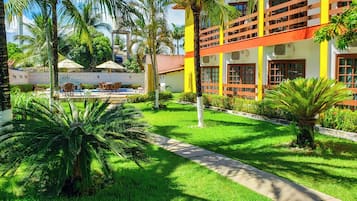 A hotel courtyard with a swimming pool, outdoor seating, and lush greenery.