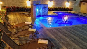Un área de piscina con sillas de descanso y una fuente de agua.