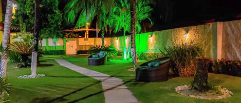 A well-maintained outdoor area with a pathway leading to a seating area, surrounded by lush greenery and palm trees.
