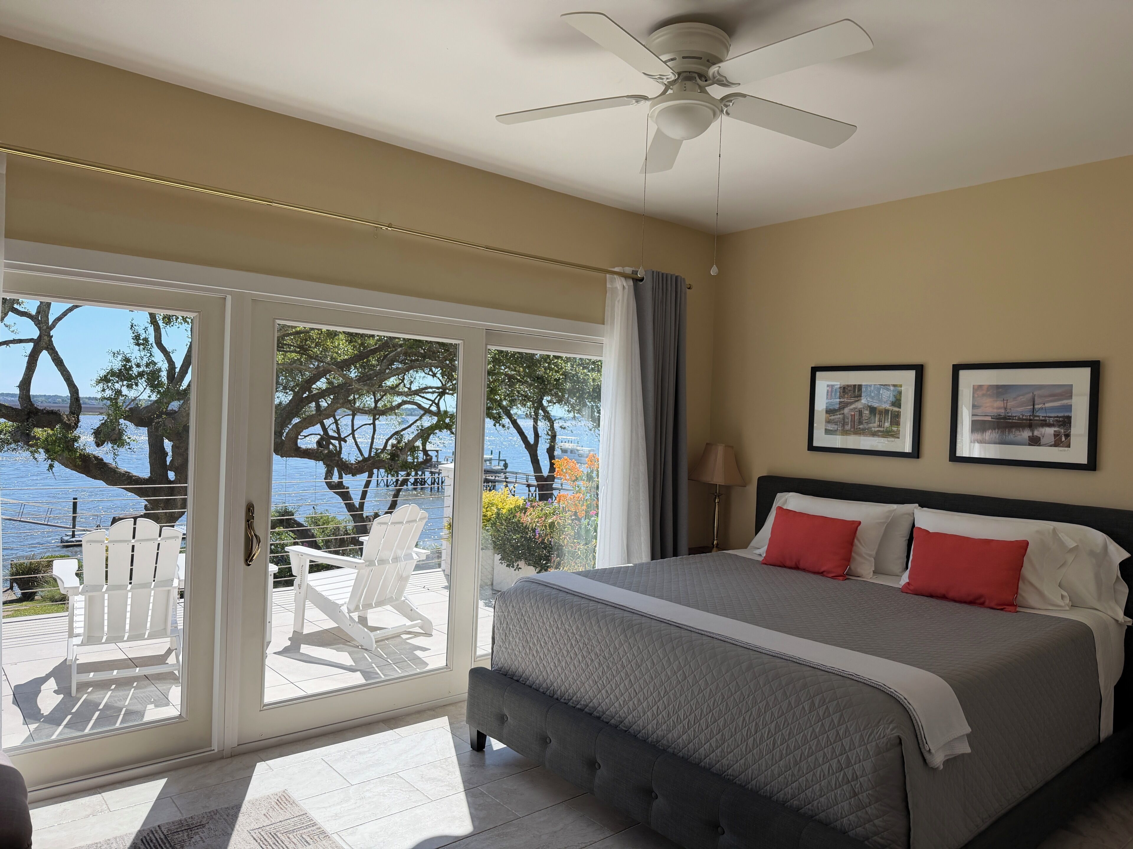 Quarto com cama, ventilador de teto e vista para o exterior.