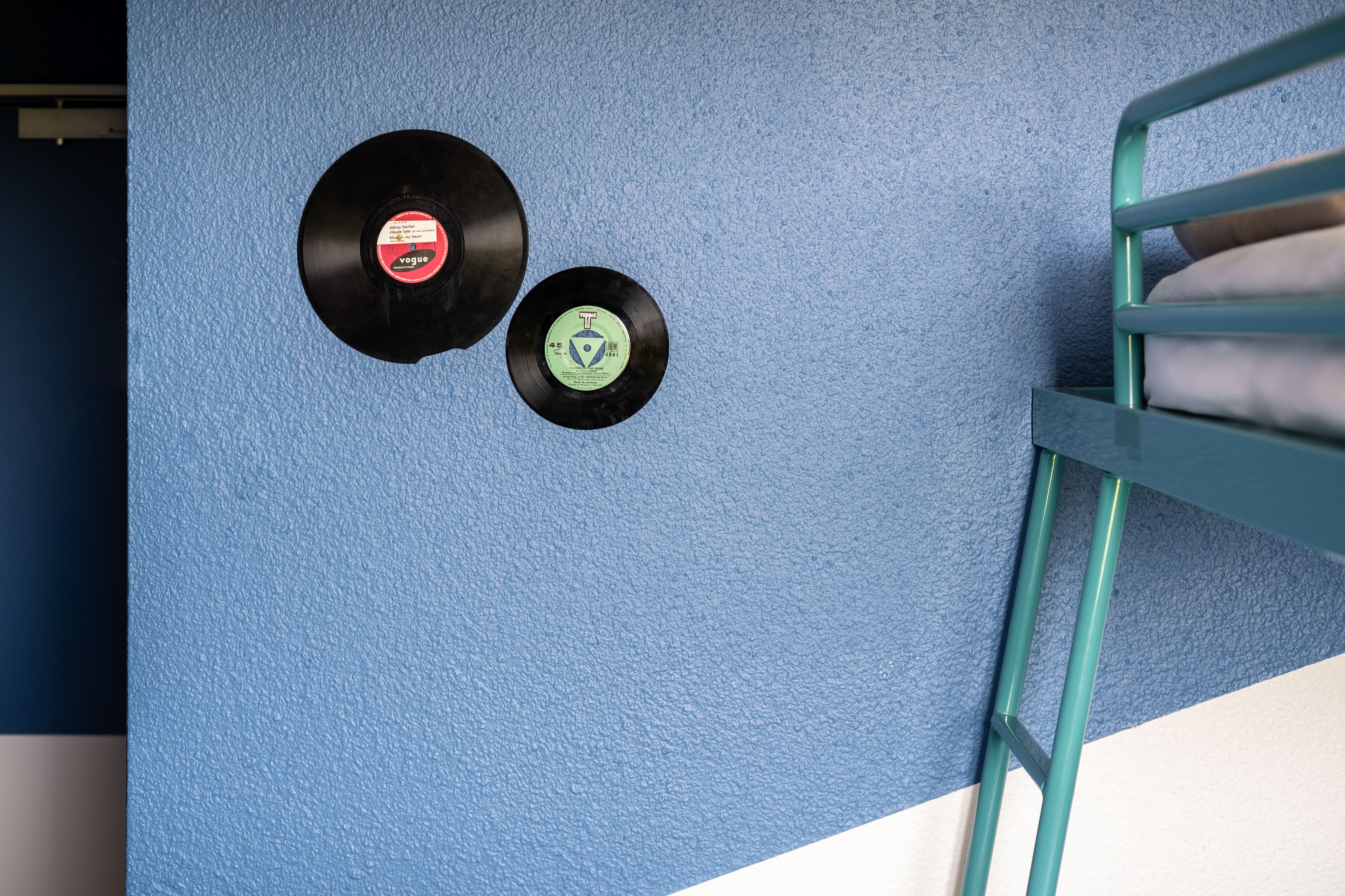 Dos discos de vinilo montados en una pared azul con textura.