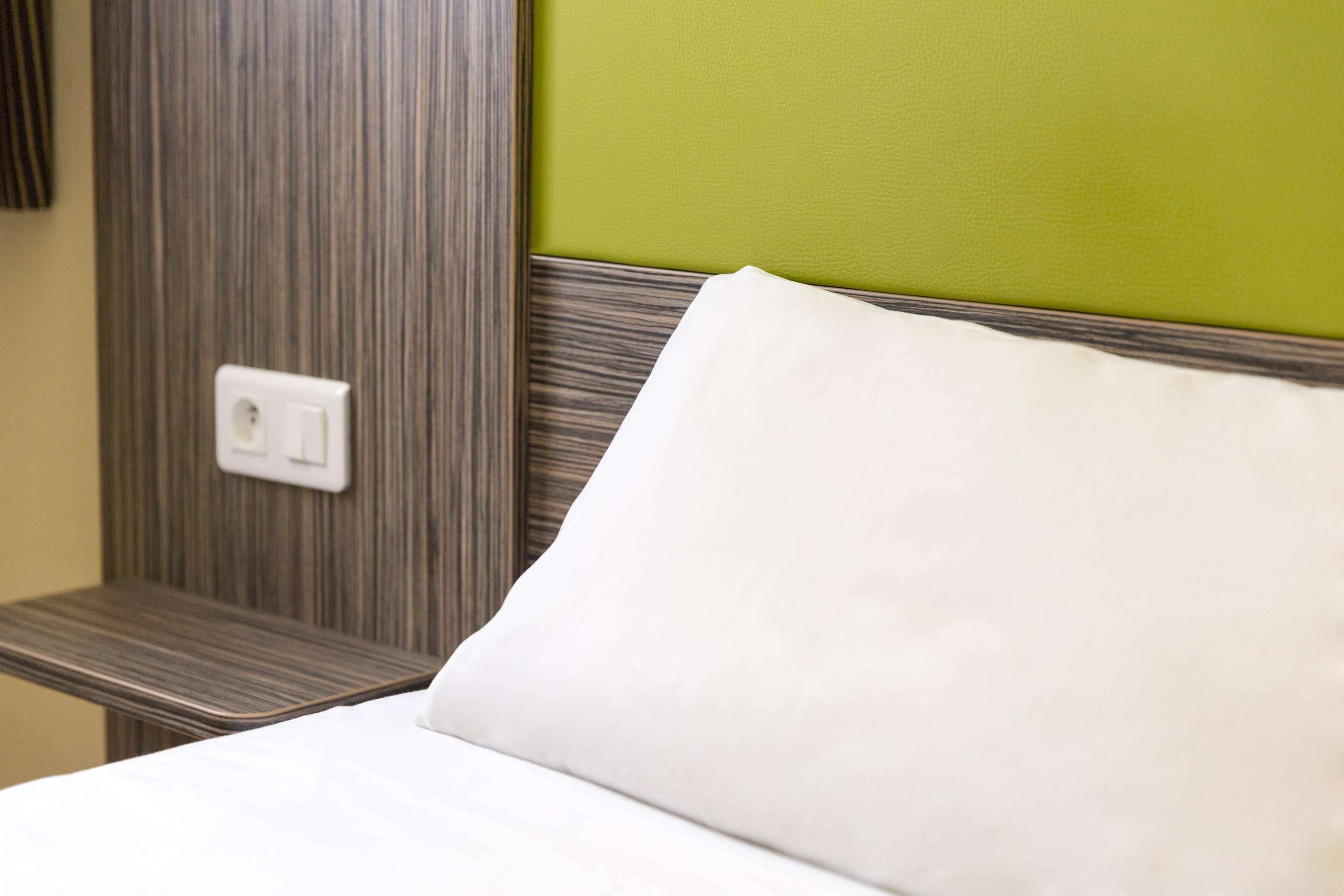 Une chambre d’hôtel avec un lit, une prise de courant et un mur vert.