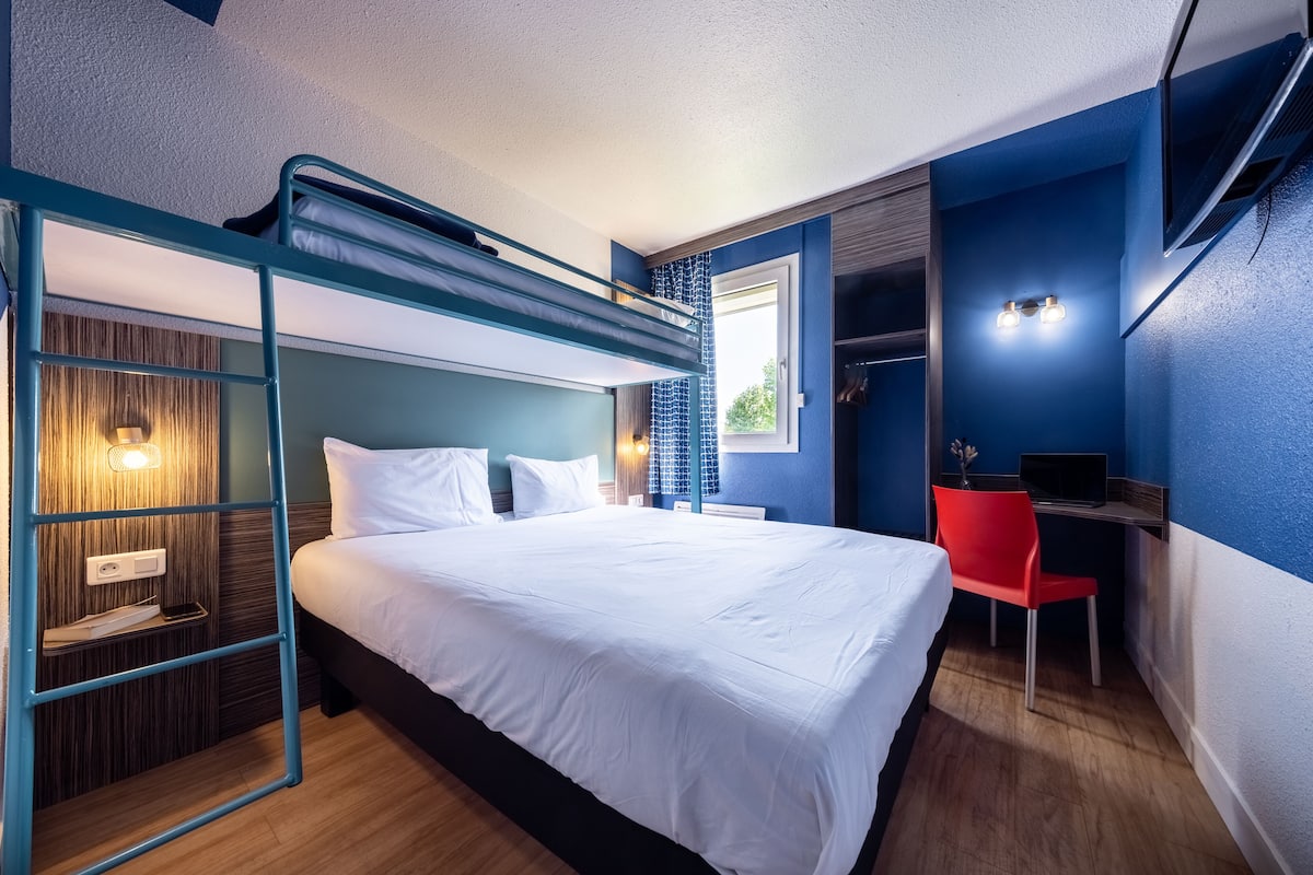 A modern bedroom with a bunk bed, a desk with a chair, and a wardrobe.