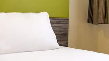 Una cama bien hecha con un almohadón blanco y un cabecero a rayas.