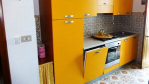 Une cuisine avec des meubles de couleur jaune, une cuisinière et un évier.